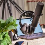 Micrófono profesional de estudio y auriculares junto a un ordenador portátil para ilustrar la estrategia de contenido cruzado entre podcast y YouTube.