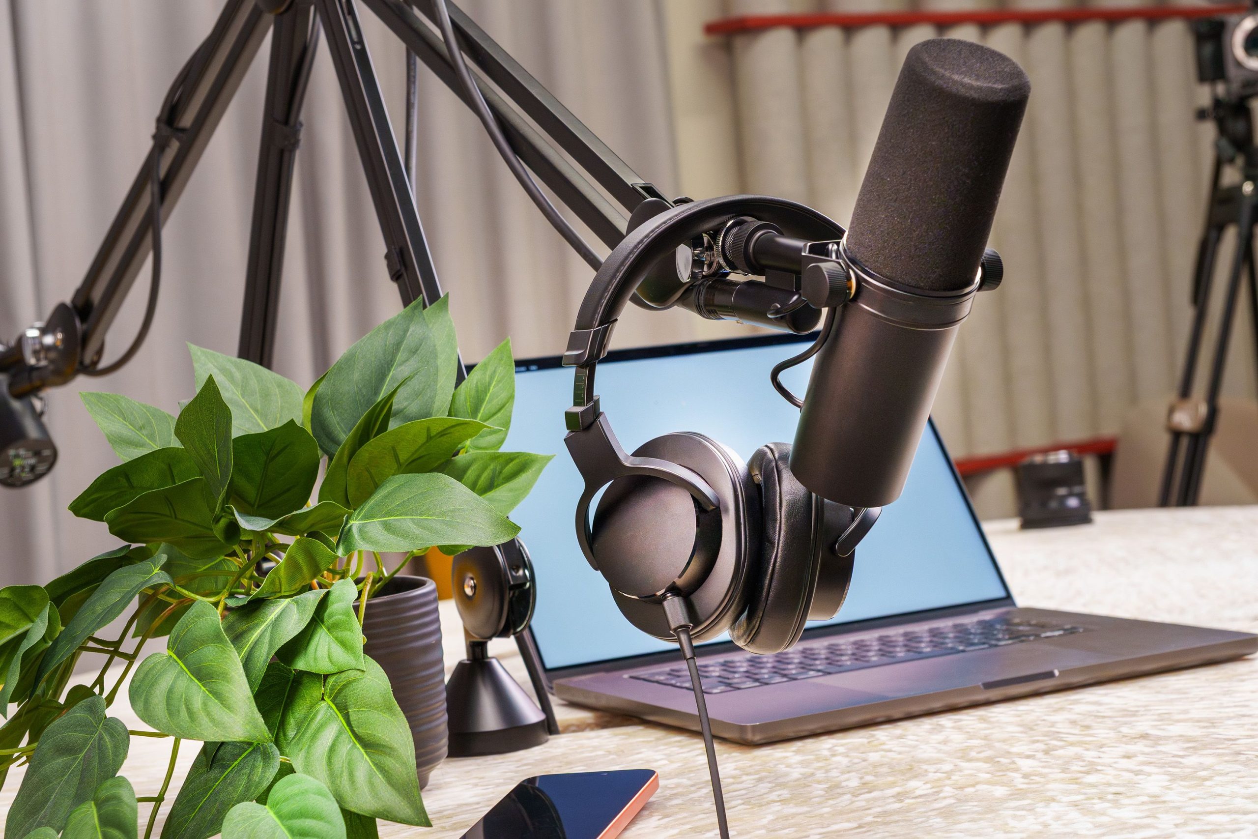 Micrófono profesional de estudio y auriculares junto a un ordenador portátil para ilustrar la estrategia de contenido cruzado entre podcast y YouTube.